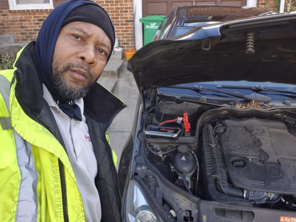 Alpha ES technician performing a battery jump start beside a customer's vehicle in Maryland